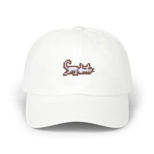 May include: White baseball cap with a pixelated white cat embroidered on the front.