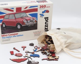 Puede incluir: Un rompecabezas de madera de 260 piezas con un Mini Cooper rojo. En la caja se puede leer "Mini Cooper The Italian Job Edition" y "HMP 7239". El rompecabezas está en una bolsa blanca con cordón.