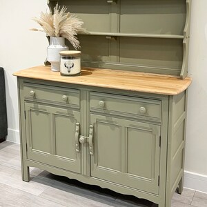 May include: A sage green painted antique dresser with a hutch. The dresser has two drawers and two doors with a wood top. The hutch has three shelves.