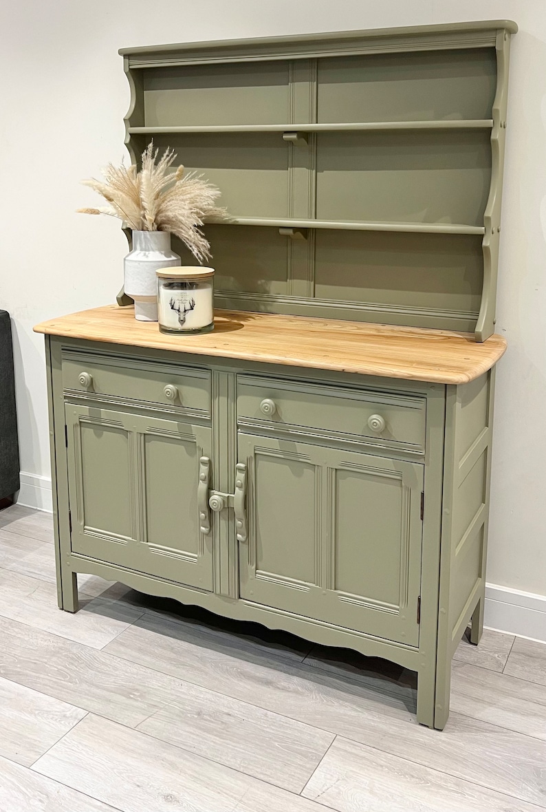 May include: A sage green painted antique dresser with a hutch. The dresser has two drawers and two doors with a wood top. The hutch has three shelves.