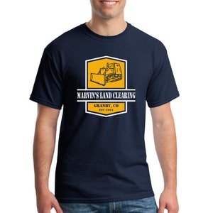 May include: A navy blue t-shirt with a yellow and white logo featuring a bulldozer and the text "Marvin's Land Clearing, Grandby, CO Est 2004".