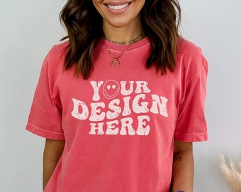 May include: A red short-sleeved t-shirt with a white graphic that says "YOUR DESIGN HERE" with a smiley face with hearts for eyes.