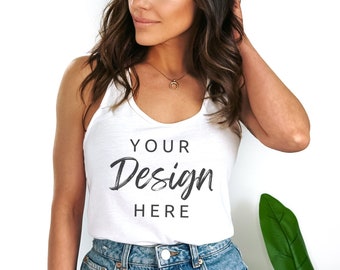 Pode incluir: Um top branco sem mangas com o texto "YOUR Design HERE" estampado na frente. O top está sendo usado por uma pessoa com cabelo longo e castanho e é combinado com shorts jeans.