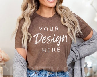 May include: A woman wearing a brown t-shirt with the text "YOUR Design HERE" in white. She is also wearing denim shorts and a grey cardigan.