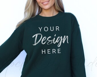 May include: A dark green sweatshirt with long sleeves and a crew neck. The sweatshirt has the text "YOUR Design HERE" printed on the front in white.