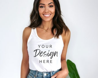 Pode incluir: Um top branco sem mangas com o texto "YOUR Design HERE" estampado na frente. O top está sendo usado por uma pessoa com cabelo castanho longo e é combinado com shorts jeans.