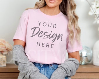 Puede incluir: Una camiseta rosa con el texto "YOUR Design HERE" en la parte delantera. La camiseta la lleva puesta una persona con el pelo largo rubio y una chaqueta de punto gris.