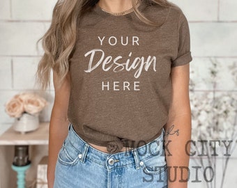 May include: A brown t-shirt with the text "Your Design Here" in white. The shirt is being worn by a person with long brown hair and is styled with blue jeans.