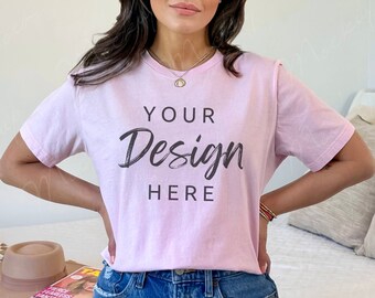 Puede incluir: Una camiseta rosa con el texto "YOUR Design HERE" en fuente de letra cursiva negra. La camiseta la lleva puesta una persona con el pelo largo y castaño y va combinada con unos vaqueros azules.