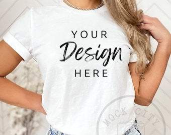 May include: A white t-shirt with the text "YOUR Design HERE" on the front. The shirt is being worn by a person with long blonde hair and is tucked into light blue jeans.