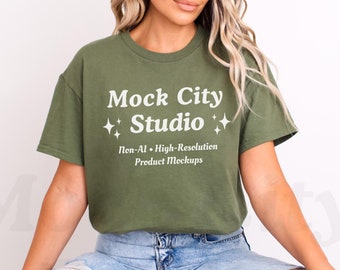 May include: A woman wearing a green t-shirt with the text "Mock City Studio" and the words "Non-AI - High-Resolution Product Mockups" printed on it. She is wearing blue jeans.