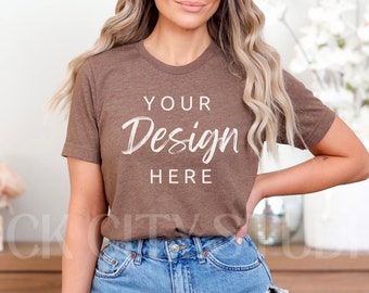May include: A brown t-shirt with the text "YOUR Design HERE" printed on the front. The t-shirt is being worn by a person with long blonde hair and is paired with denim shorts.