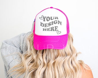 Op de afbeelding: Een roze en witte truckercap met de tekst "YOUR DESIGN HERE" en twee kleine hartjes aan de voorkant.