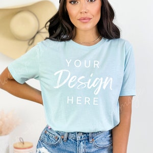 May include: A light blue t-shirt with short sleeves and a crew neck. The shirt has the text "YOUR Design HERE" printed on the front in white.