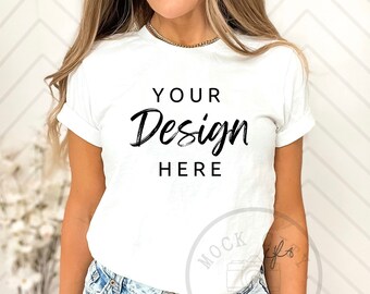 May include: A white t-shirt with the text "YOUR Design HERE" on the front. The shirt is being worn by a person with long blonde hair and is paired with light blue jeans.