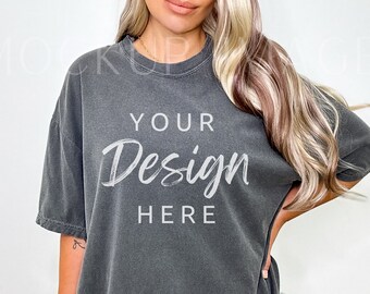 Puede incluir: Una camiseta gris antracita de gran tamaño con un ajuste holgado. La camiseta tiene cuello redondo y mangas cortas. El texto "YOUR Design HERE" está impreso en blanco en la parte delantera de la camiseta.