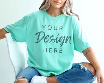 May include: A turquoise blue t-shirt with the text "YOUR Design HERE" in a dark gray font. The shirt is oversized and has a relaxed fit.