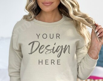 May include: A beige sweatshirt with the text "YOUR Design HERE" printed on the front. The sweatshirt is being worn by a person with long blonde hair.