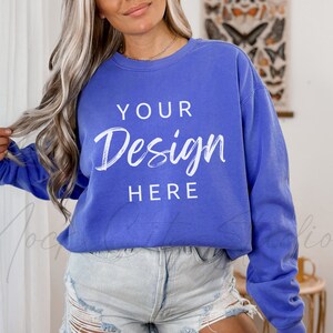 May include: A woman wearing a blue sweatshirt with the text "YOUR Design HERE" printed on the front. She is wearing denim shorts and has long blonde hair.