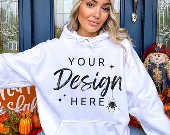 May include: White hooded sweatshirt with the text "YOUR Design HERE" and a small spider graphic. The model is wearing the sweatshirt with a beige beanie.