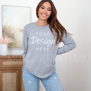 May include: A gray long-sleeved shirt with the text "YOUR Design HERE" printed on the front. The shirt is being worn by a person with long brown hair.