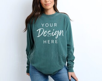 Puede incluir: Una camiseta de manga larga de color verde azulado con el texto "YOUR Design HERE" impreso en la parte delantera.