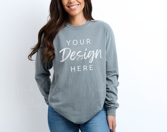 Puede incluir: Una camiseta de manga larga de color azul claro con cuello redondo. La camiseta tiene el texto "YOUR Design HERE" impreso en blanco en la parte delantera.