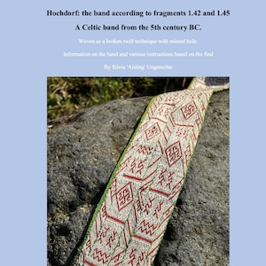May include: A close-up of a woven Celtic band from the 5th century BC. The band is made of white, green and red thread and is resting on a grey rock. The band is woven in a broken twill technique with a missed hole.