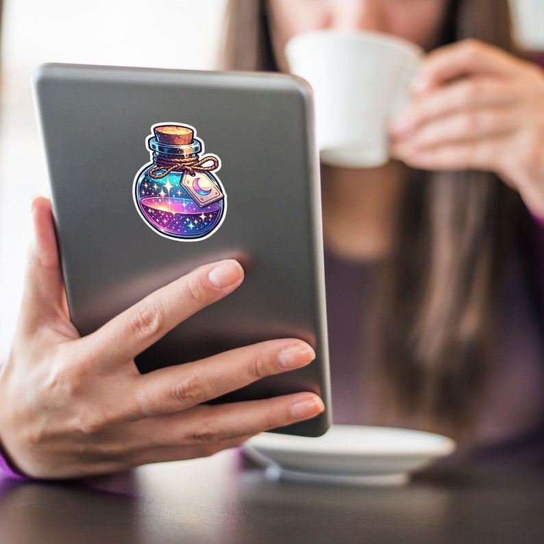 May include: A sticker of a glass bottle filled with a swirling galaxy-like liquid. The bottle has a cork stopper and a tag with a crescent moon on it.