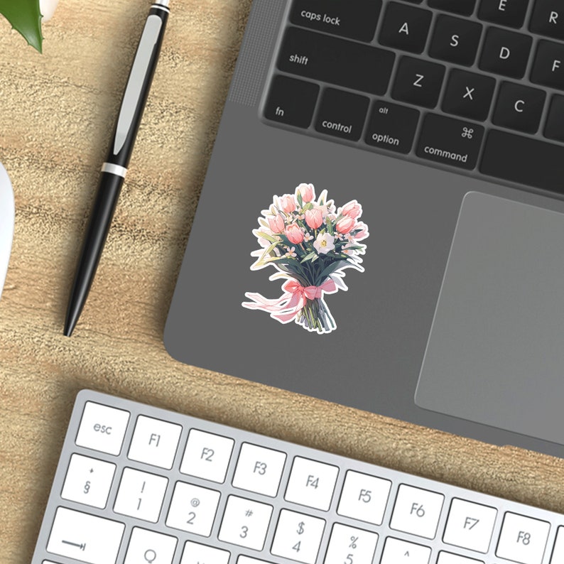 May include: A bouquet of pink and white tulips tied with a pink ribbon. The bouquet is on a gray laptop.