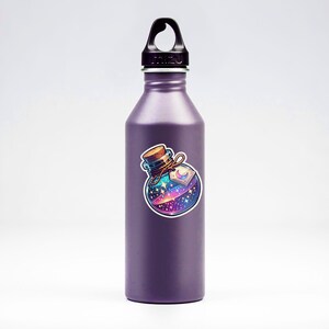May include: A purple reusable water bottle with a sticker of a glass bottle filled with a swirling galaxy. The bottle has a black lid with a carrying loop.
