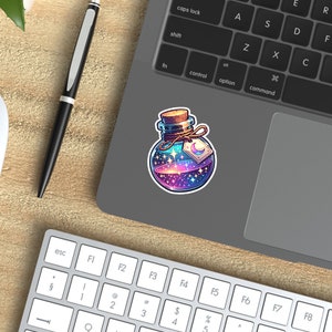 May include: A glass bottle with a cork stopper filled with a swirling galaxy of stars and a crescent moon. The bottle is tied with a string and has a tag with a crescent moon.