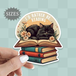 May include: A black cat sleeps on a stack of books with a white background. The books have a vintage look and the cat is surrounded by flowers. The text "I'd rather be reading" is written in a white circle above the cat.