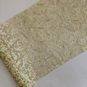 May include: A gold and white table runner with a delicate floral pattern. The runner is made of a sheer fabric with a subtle shimmer.