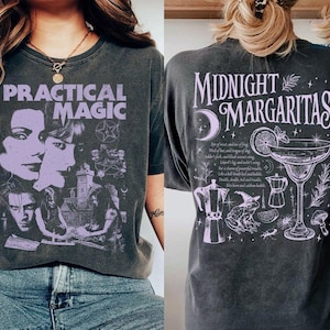 Könnte beinhalten: Ein anthrazitfarbenes T-Shirt mit violettem Grafikdruck. Die Vorderseite zeigt den Text "PRACTICAL MAGIC" mit Gesichtern und einem Gebäude. Die Rückseite zeigt den Text "MIDNIGHT MARGARITAS" mit einem Cocktailglas, einem Frosch und Kaffeekannen.