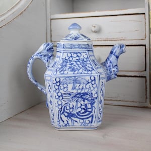 Peut inclure: Une théière en porcelaine bleue et blanche avec des anses en forme de dragon. La théière présente un motif géométrique avec des motifs floraux et de dragons.