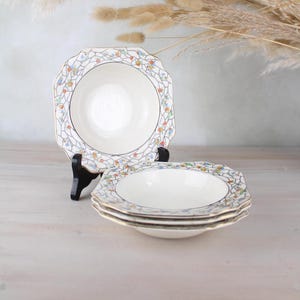 Peut inclure: Quatre bols en céramique blanche avec un motif floral et une bordure dorée. Les bols sont empilés les uns sur les autres.