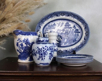May include: A set of blue and white china featuring a traditional willow pattern. The set includes a pitcher, a jar, a salt and pepper shaker, and a platter with three plates.