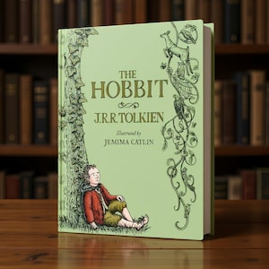 May include: A hardcover edition of "The Hobbit" by J.R.R. Tolkien, illustrated by Jemima Catlin. The book features a light green cover with the title in gold lettering and a whimsical illustration of a boy and a tree. The book is displayed on a wooden surface.