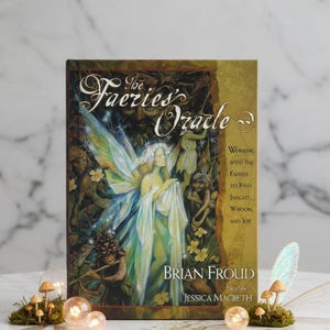 May include: A copy of 'The Faeries' Oracle' book, featuring a fairy illustration on the cover. The title is in a decorative font, and the cover has a green and gold design. Fairy-themed decorations, including miniature mushrooms and fairy wings, surround the book.