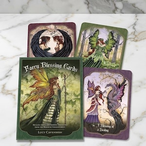 Può includere: Un mazzo di carte Faern Blessing con illustrazioni di fate e draghi. La scatola verde recita "Faern Blessing Cards" e "Healing Gifts and Shining Treasures from the Realm of Enchantment" di Lucy Cavendish. Tema fantasy.