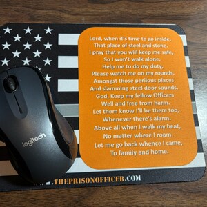Pode incluir: Rato de computador Logitech preto em um mousepad com um design de bandeira americana de linha azul fina e um poema. O mousepad tem o texto: THEPRISONOFFICER.COM.