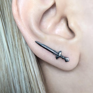 May include: A pair of black sword earrings. The swords are detailed and have a slightly curved blade.