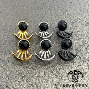 Puede incluir: Tres pares de pendientes con detalles de piedras preciosas negras. Los pendientes est&aacute;n hechos de metal dorado, plateado y negro. Cada pendiente presenta un dise&ntilde;o de media luna con un patr&oacute;n de rayos de sol.