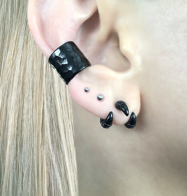 May include: Black ear cuff with a hammered texture, two small silver stud earrings, and a pair of black claw earrings.