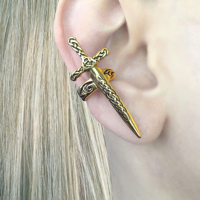 May include: Gold-toned ear cuff in the shape of a sword with a Celtic knot design.