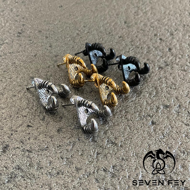 May include: Three pairs of earrings with a claw design. The earrings are made of metal and come in silver, gold, and black.