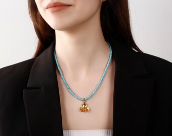 May include: A turquoise beaded necklace with a gold flower pendant.