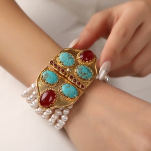 May include: A gold bracelet with turquoise and red stones, accented with a pearl strand.