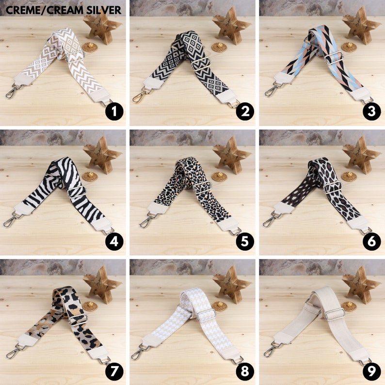 May include: Nine different patterned and solid color adjustable straps for bags. The straps are made of a woven fabric and have a silver metal buckle. The straps are displayed on a wooden surface with a star-shaped decoration.